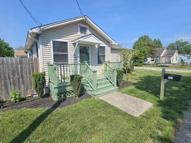 shotgun-style home with fence, a wooden deck, and a front lawn