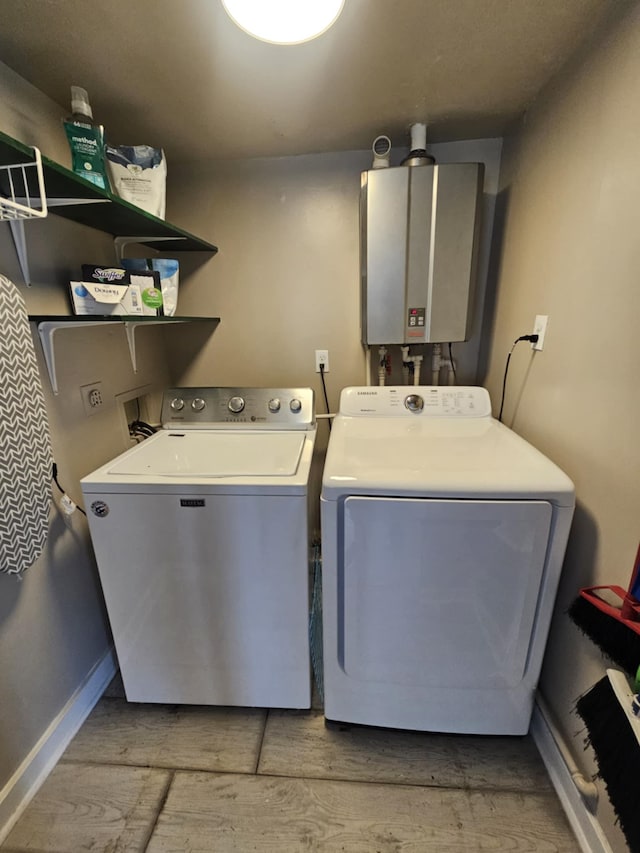 washroom with washing machine and clothes dryer, laundry area, light wood-style floors, water heater, and baseboards