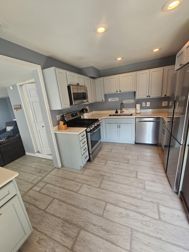 kitchen with a sink, light countertops, stainless steel appliances, recessed lighting, and light wood-type flooring