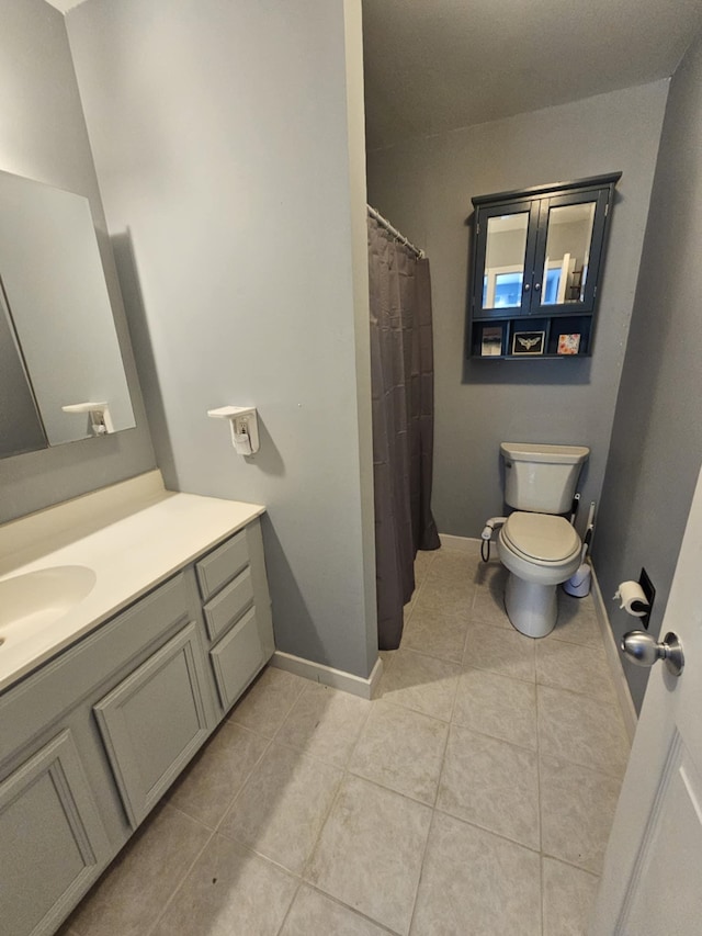 full bathroom featuring toilet, tile patterned floors, baseboards, and vanity