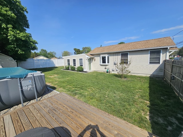 rear view of property with a fenced backyard, a fenced in pool, a wooden deck, and a yard