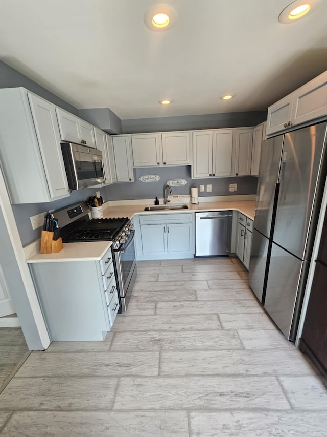 kitchen with light wood-type flooring, a sink, appliances with stainless steel finishes, and light countertops
