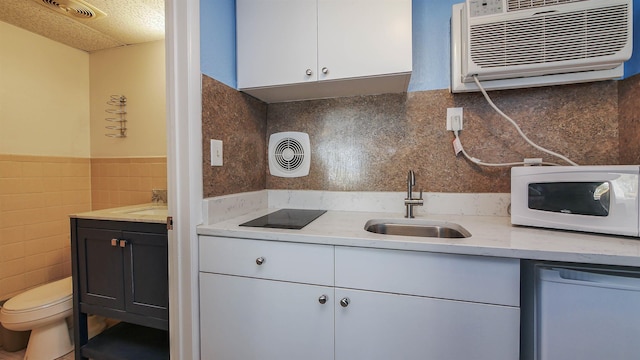 kitchen featuring a sink, white appliances, white cabinetry, tile walls, and a wainscoted wall