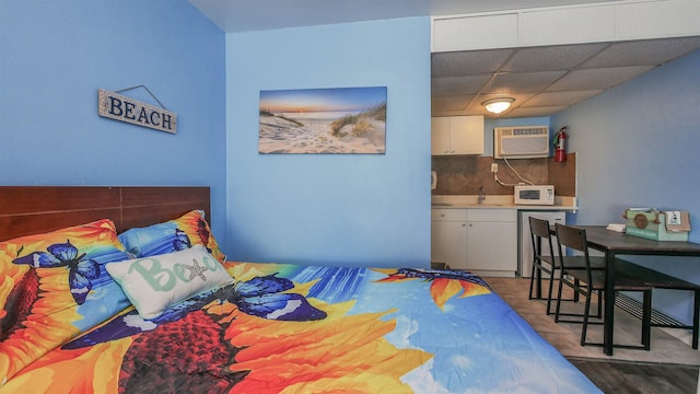 bedroom featuring an AC wall unit, a drop ceiling, and a sink