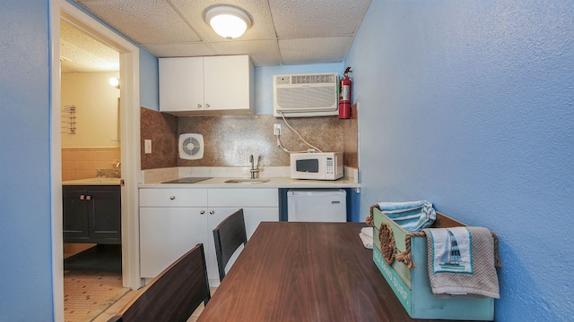 kitchen with white appliances, a sink, decorative backsplash, white cabinets, and light countertops
