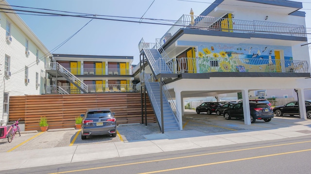 view of building exterior with stairs and covered and uncovered parking