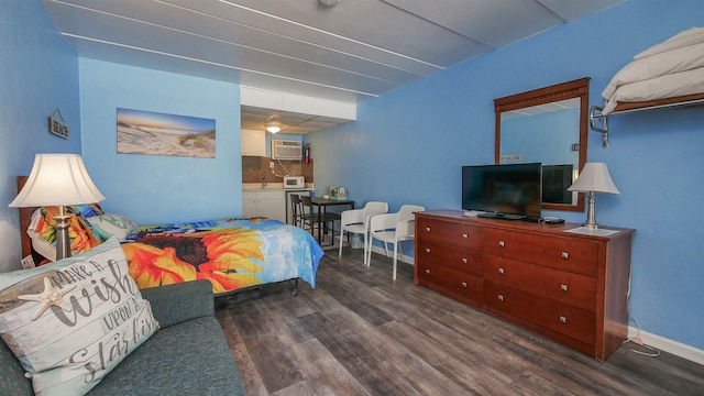 bedroom with wood finished floors, baseboards, and an AC wall unit
