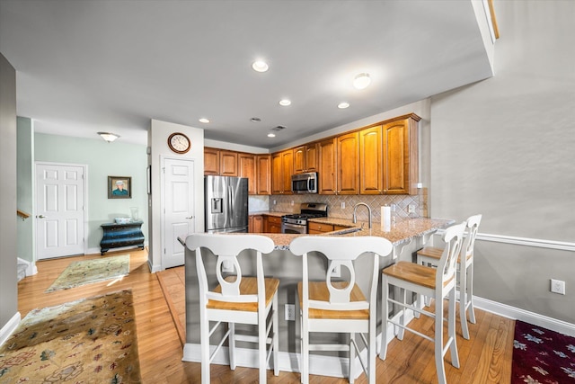 kitchen with stainless steel appliances, backsplash, a kitchen breakfast bar, and kitchen peninsula