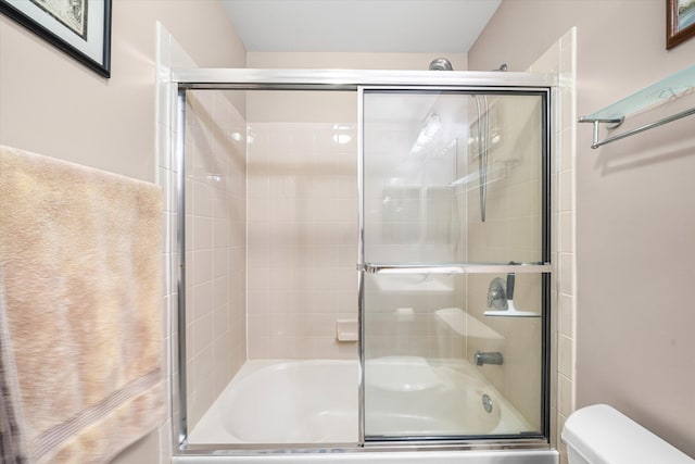 bathroom featuring combined bath / shower with glass door and toilet