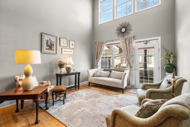 living room with plenty of natural light, a towering ceiling, and hardwood / wood-style floors