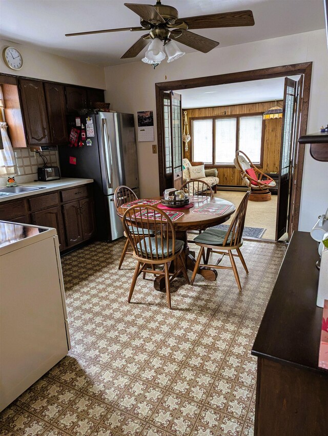 living area featuring carpet floors, ceiling fan, and wooden walls