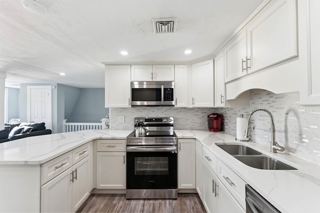 140 E Burk Ave Unit A, Wildwood, NJ 08260 - kitchen featuring appliances with stainless steel finishes, a peninsula, white cabinetry, wood finished floors, and light stone countertops