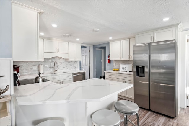 140 E Burk Ave Unit A, Wildwood, NJ 08260 - kitchen with appliances with stainless steel finishes, a peninsula, light wood-style flooring, backsplash, and a breakfast bar
