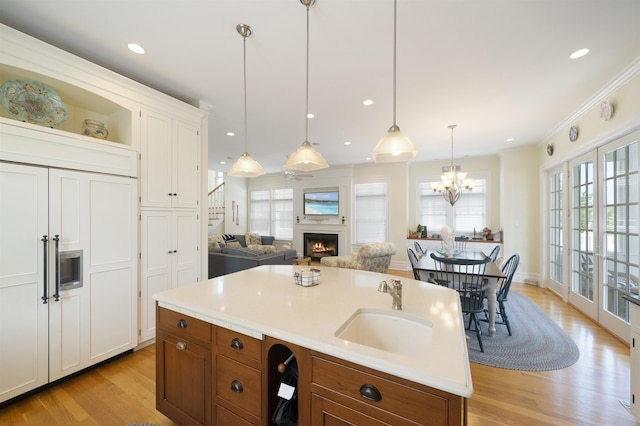 261 45th St, Avalon, NJ 08202 - kitchen featuring brown cabinets, light wood-type flooring, a lit fireplace, white cabinets, and decorative light fixtures