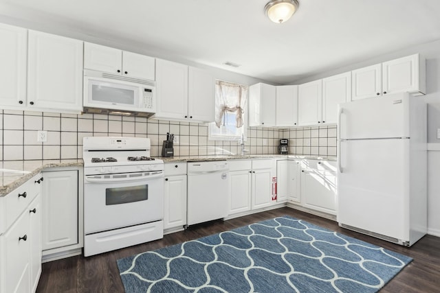 kitchen with white cabinets, dark hardwood / wood-style flooring, white appliances, and light stone counters