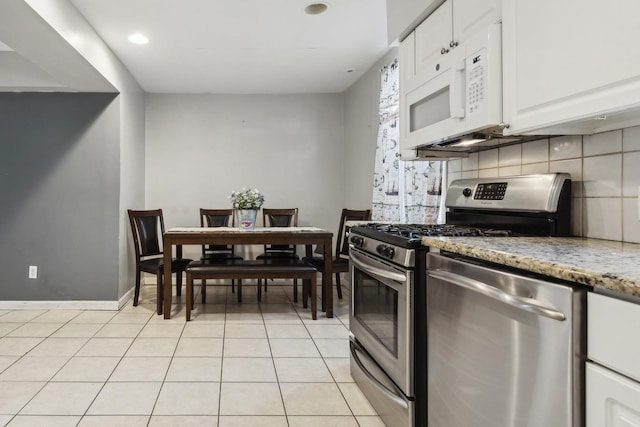 kitchen featuring white cabinetry, light stone counters, decorative backsplash, light tile patterned floors, and appliances with stainless steel finishes