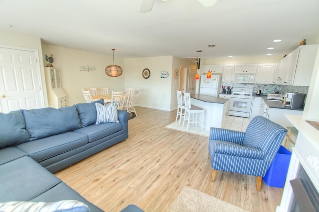 living room with ceiling fan and light wood-type flooring