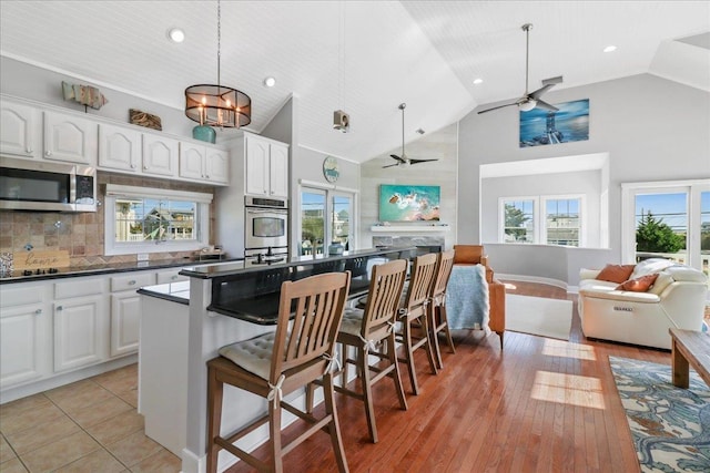 kitchen featuring stainless steel appliances, dark countertops, open floor plan, and a kitchen breakfast bar