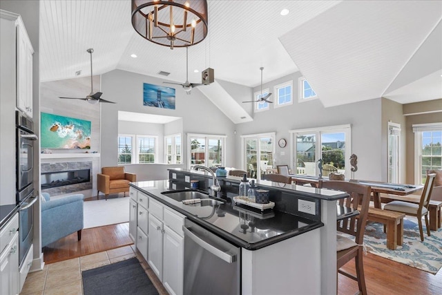 kitchen featuring white cabinets, dark countertops, an island with sink, appliances with stainless steel finishes, and open floor plan