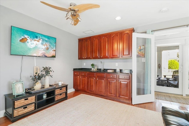 kitchen with dark countertops, light wood-type flooring, baseboards, and ceiling fan