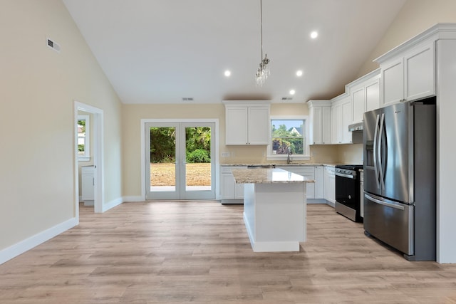 kitchen with light stone countertops, appliances with stainless steel finishes, decorative light fixtures, a center island, and white cabinetry