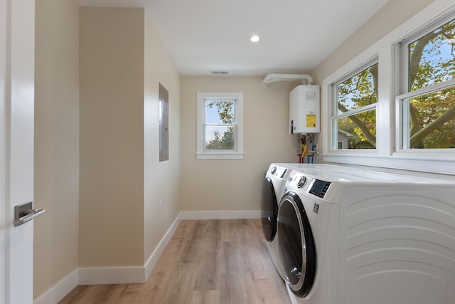 clothes washing area with a healthy amount of sunlight, light hardwood / wood-style flooring, tankless water heater, and independent washer and dryer