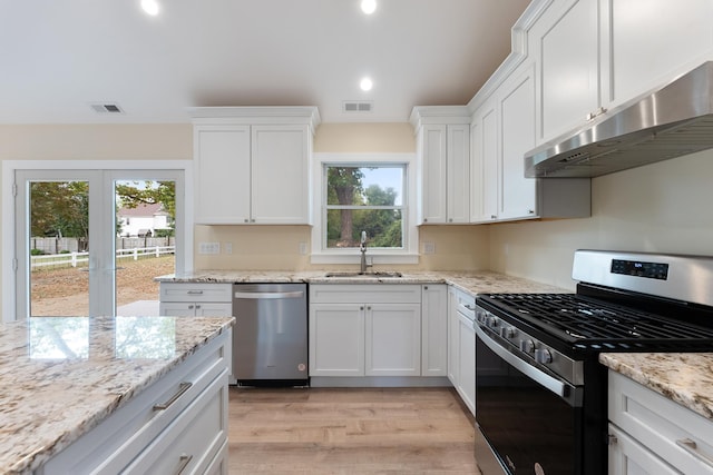 kitchen with light wood-type flooring, light stone counters, stainless steel appliances, sink, and white cabinets