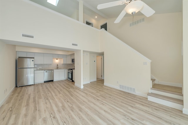 24 Heron Way N, Cape May, NJ 08204 - unfurnished living room with a sink, stairway, high vaulted ceiling, light wood finished floors, and a ceiling fan
