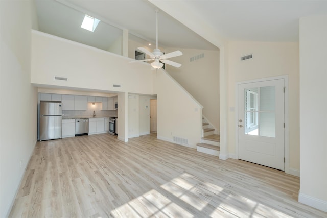 24 Heron Way N, Cape May, NJ 08204 - unfurnished living room with light wood-style floors, stairway, high vaulted ceiling, ceiling fan, and baseboards