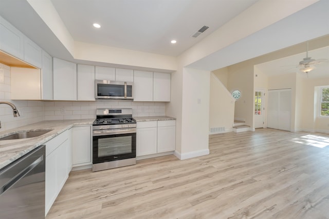 24 Heron Way N, Cape May, NJ 08204 - kitchen with stainless steel appliances, a sink, decorative backsplash, light stone counters, and light wood finished floors