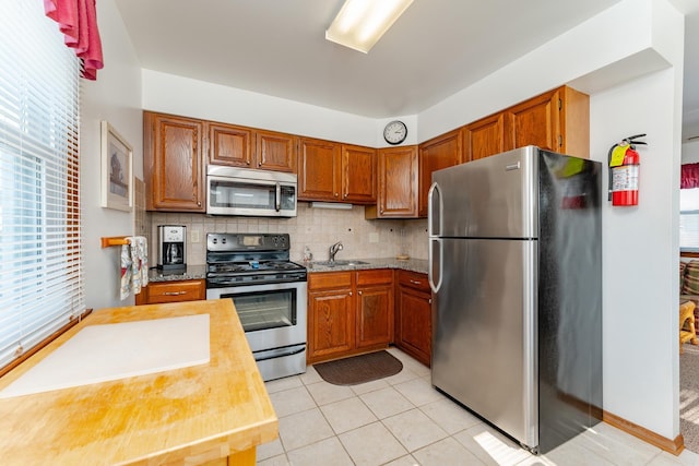 kitchen with sink, light tile patterned floors, stainless steel appliances, and tasteful backsplash