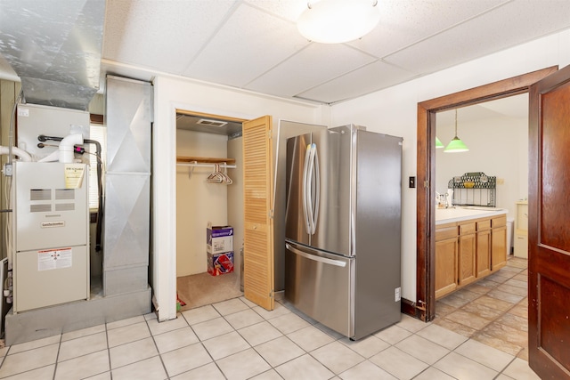 kitchen featuring a paneled ceiling, stainless steel fridge, heating unit, and hanging light fixtures