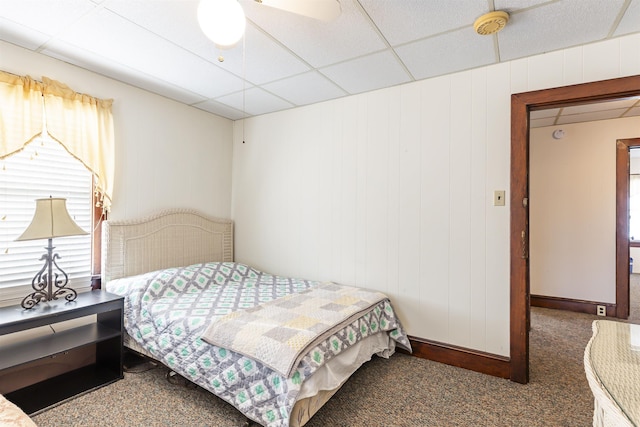 carpeted bedroom featuring multiple windows, a drop ceiling, and ceiling fan