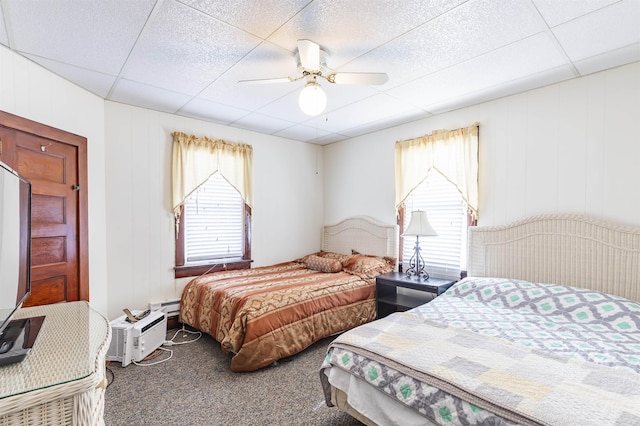 carpeted bedroom with a paneled ceiling and ceiling fan