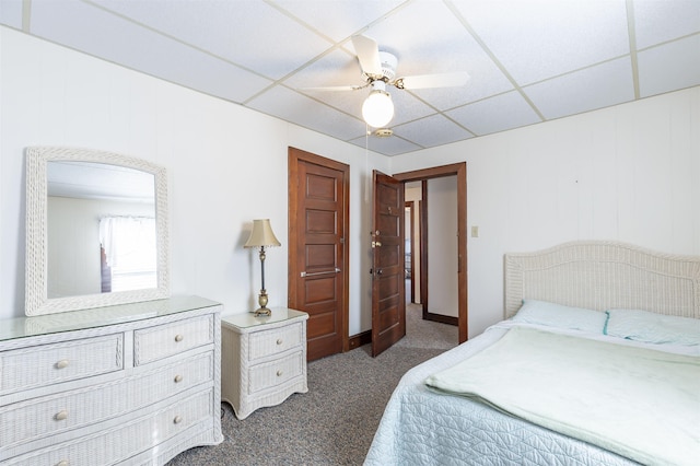 bedroom with a paneled ceiling, ceiling fan, and dark carpet