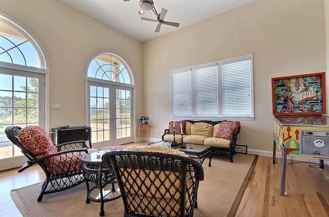 sitting room with french doors, light hardwood / wood-style flooring, ceiling fan, and a healthy amount of sunlight