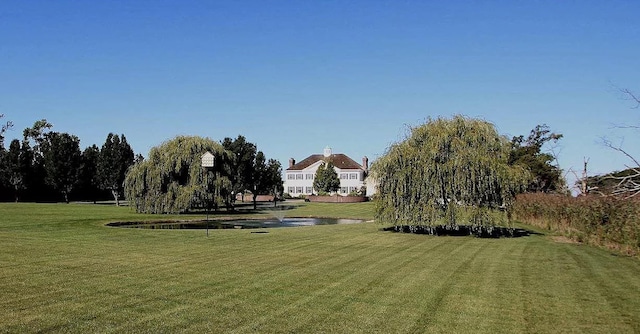 view of property's community with a lawn and a water view