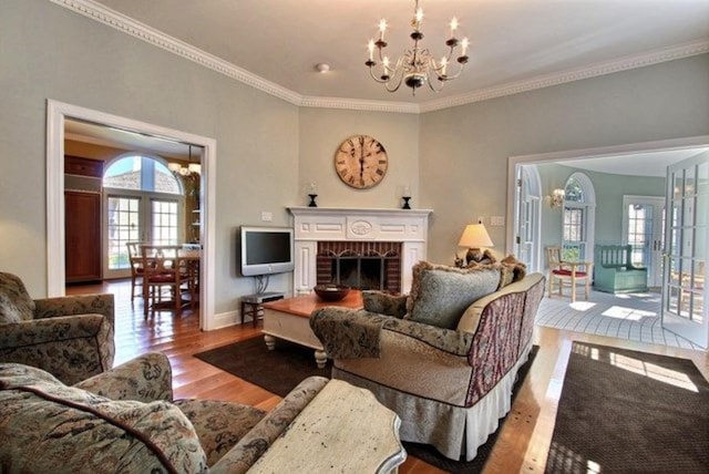 living room with crown molding, plenty of natural light, light hardwood / wood-style floors, and a notable chandelier