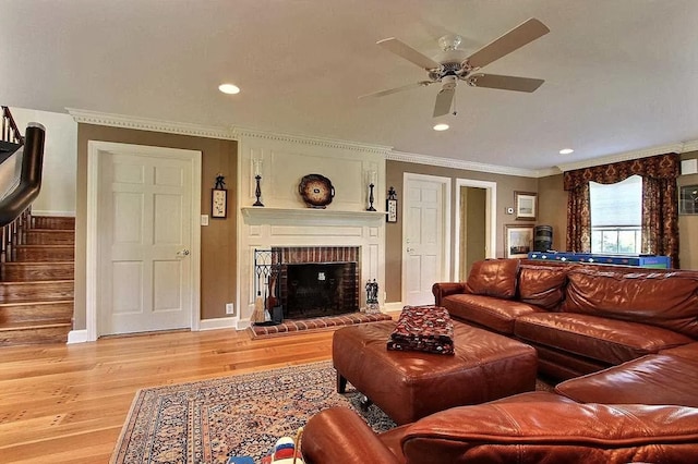 living room featuring a fireplace, light hardwood / wood-style flooring, ceiling fan, and ornamental molding