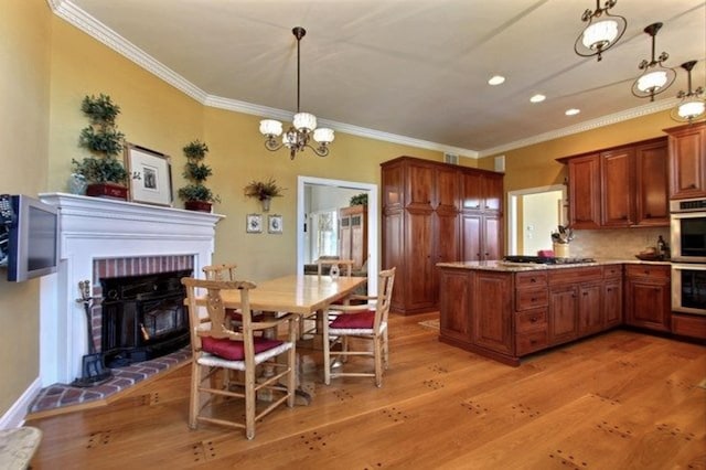 kitchen featuring a brick fireplace, tasteful backsplash, an inviting chandelier, light hardwood / wood-style flooring, and decorative light fixtures