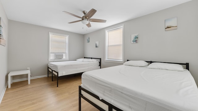 bedroom with light hardwood / wood-style floors, ceiling fan, and cooling unit