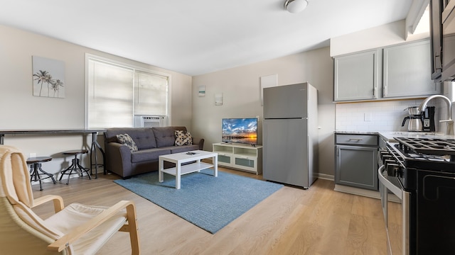 kitchen with tasteful backsplash, gray cabinetry, stainless steel appliances, and light wood-type flooring