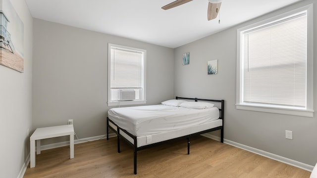 bedroom featuring light hardwood / wood-style floors, ceiling fan, and cooling unit