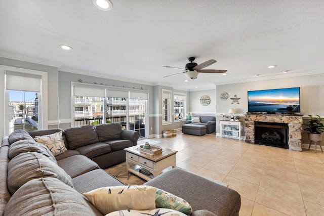 living room with ceiling fan, a stone fireplace, light tile patterned flooring, recessed lighting, and crown molding