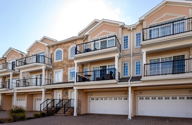 exterior space featuring decorative driveway, an attached garage, and stucco siding