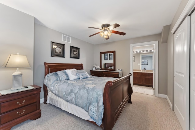 bedroom featuring baseboards, visible vents, connected bathroom, light colored carpet, and a closet