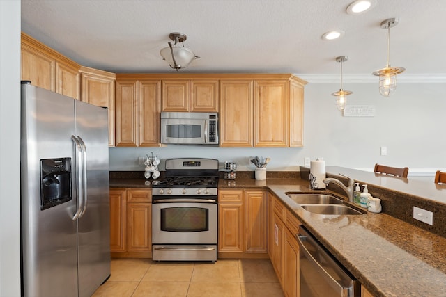 kitchen with decorative light fixtures, light tile patterned floors, appliances with stainless steel finishes, a sink, and dark stone countertops