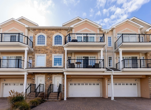 view of property featuring decorative driveway, an attached garage, and stucco siding