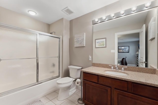 bathroom featuring bath / shower combo with glass door, visible vents, toilet, vanity, and tile patterned floors