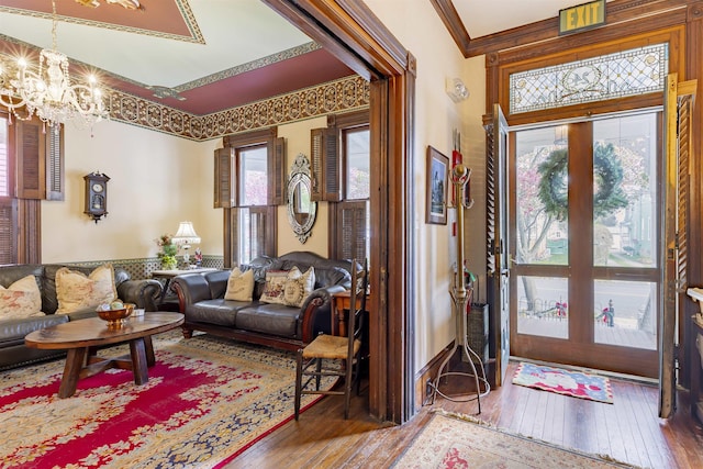 foyer entrance with hardwood / wood-style flooring, an inviting chandelier, and ornamental molding